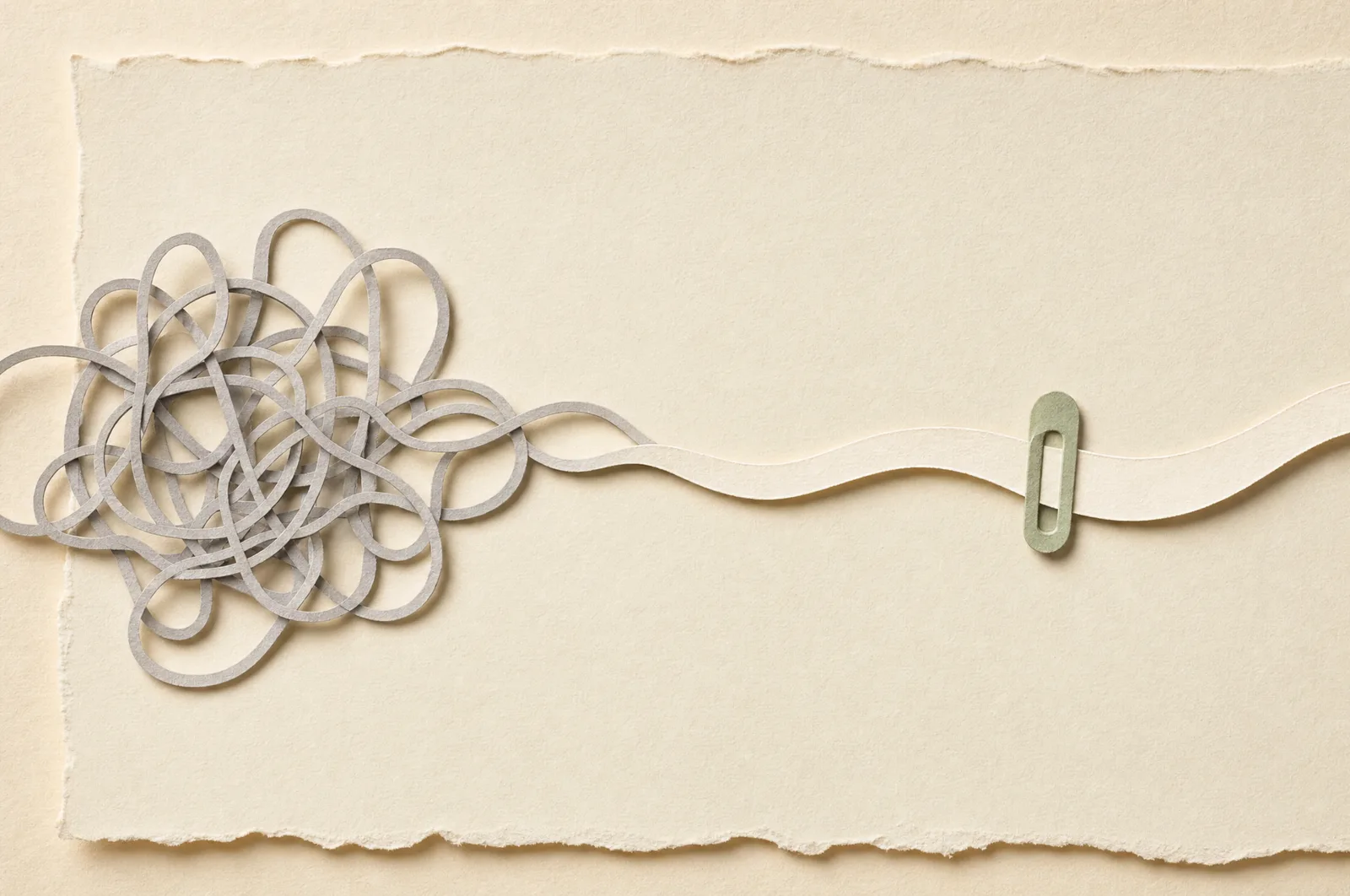 A tangle of grey paper thread resolving into one smooth cream ribbon held by a sage clip